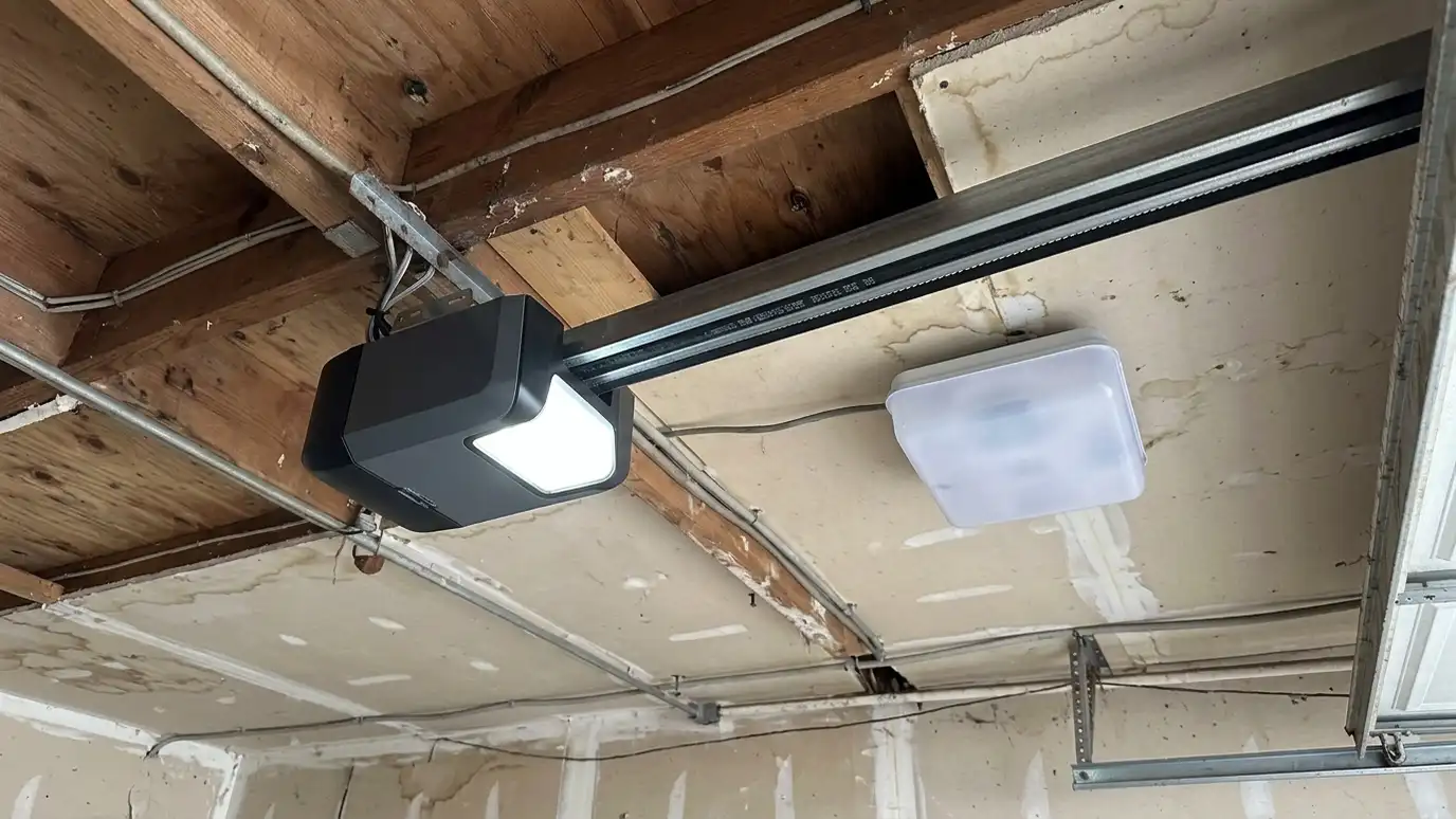After: A tired chain opener replaced by a sleek belt-drive unit | Music City Garage Door Service After: a garage ceiling with a new belt-drive opener with a bright light and a tidy rail