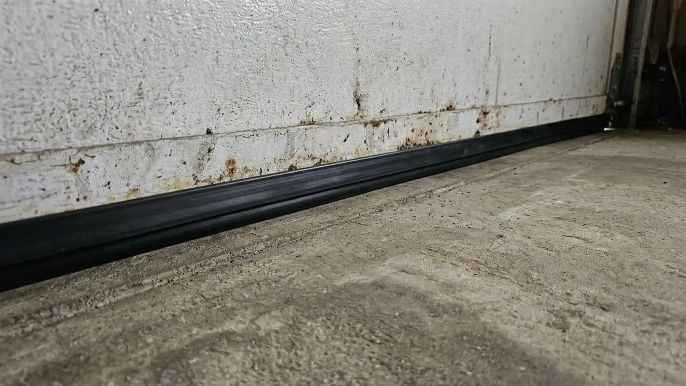 After: A gap under the door closed with a new seal | Music City Garage Door Service After: the bottom of a garage door with a new black rubber seal tight against the floor