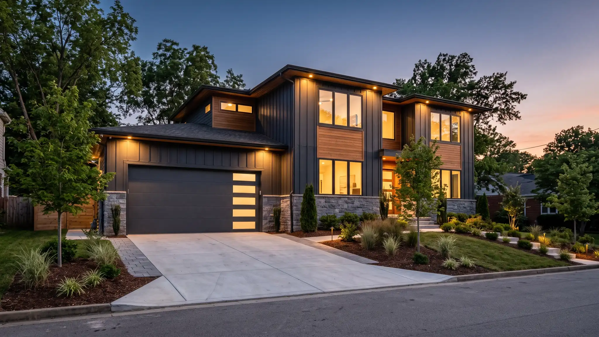 Music City Garage Door Service | Nashville, TN A beautiful modern Nashville home at dusk with a wide two-car garage fitted with sleek charcoal horizontal-panel garage doors with frosted glass strips and warm lights glowing